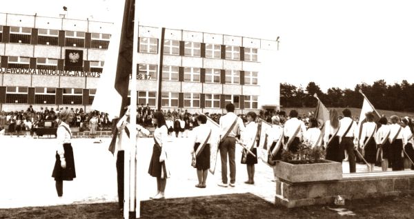 Wojewódzka inauguracja nowego roku szkolnego 1986/1987 w SP nr 8. na pierwszym planie tyłem odwrócone poczty sztandarowe w tle budynek szkoły