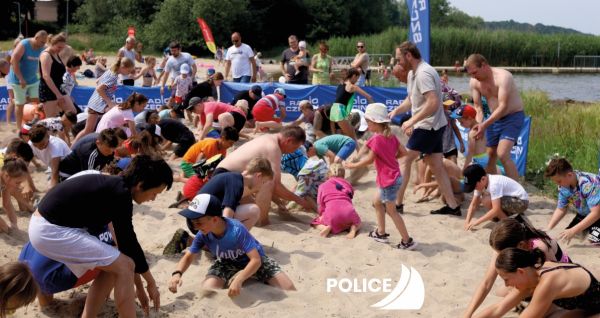 Dzieci i dorośli podczas szukania skarbów zakopanych na plaży w Trzebieży