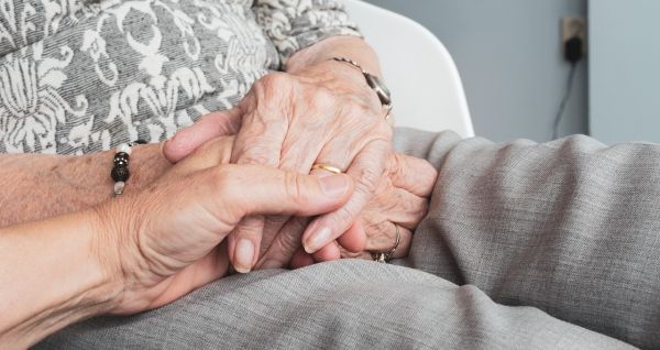 osoba trzymającą starszą osobę za rękę